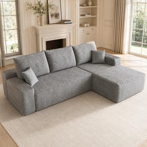 May include: A light gray sectional sofa featuring a textured corduroy fabric, three large back cushions, a chaise lounge section on the right side, and two small square throw pillows placed on the seat cushions.
