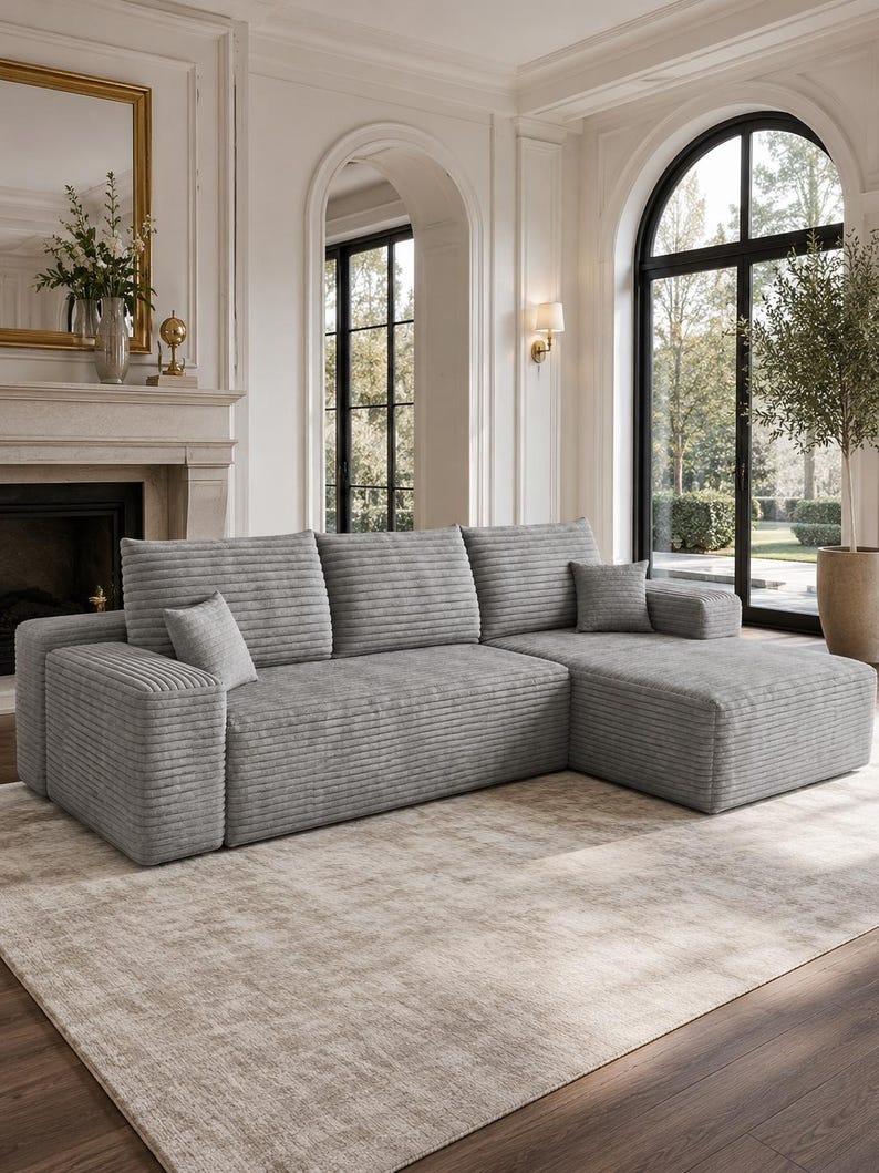 May include: A light gray sectional sofa featuring a textured corduroy-style fabric, three back cushions, and a chaise lounge section on the right side. The sofa includes two small square throw pillows in the same matching gray fabric.