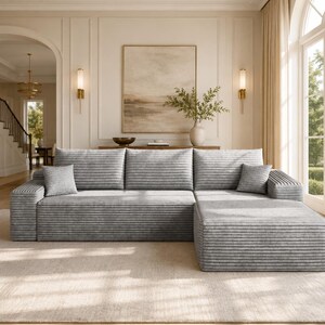May include: A light gray sectional sofa featuring a horizontal ribbed texture across the backrests, seat cushions, and armrests. The sofa includes two square throw pillows in a matching gray fabric, positioned on the left and right sides.
