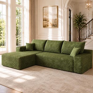 May include: A large L-shaped sectional sofa upholstered in olive green corduroy fabric. The sofa features a chaise lounge section on the left, three wide back cushions, and two small square throw pillows placed on the seat cushions.