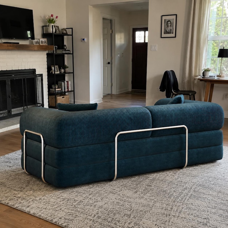 May include: A deep teal corduroy sofa featuring a horizontal ribbed texture and a structured, low-profile design. The piece is framed by a sleek, silver-toned metal support structure that wraps around the exterior base and back of the cushions.