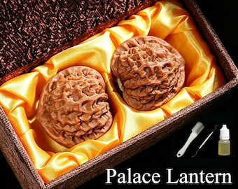Puede incluir: Dos nueces Wenwan Palace Lantern de color marrón con cáscaras profundamente texturizadas, colocadas en una caja marrón forrada con tela de satén amarilla. El set incluye un cepillo de limpieza blanco, una herramienta de metal y un frasco de aceite.