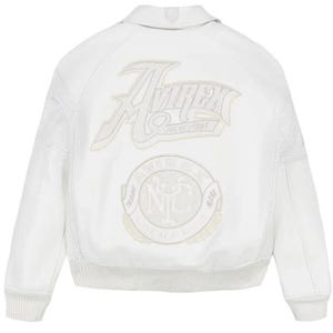 May include: A white leather bomber jacket featuring a large embroidered Avirex New York logo on the upper back and a circular Avirex NYC trade mark patch below it. The jacket includes a collared neckline, ribbed cuffs, and perforated leather panels.
