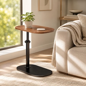 May include: A height-adjustable side table with an oval-shaped wooden top and a black metal base. The table features a central vertical support column with a manual adjustment knob, a flat oval base, and a smooth wood grain finish on the tabletop.
