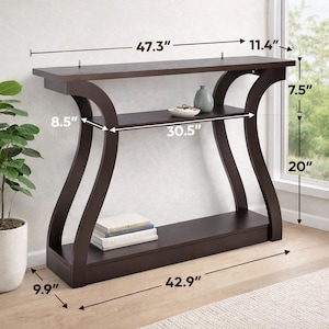 May include: A dark brown console table with curved side supports, a top surface, a middle shelf, and a bottom base. Dimensions are labeled as 47.3 inches wide, 11.4 inches deep, 7.5 inches shelf height, 20 inches shelf clearance, and 42.9 inches base.