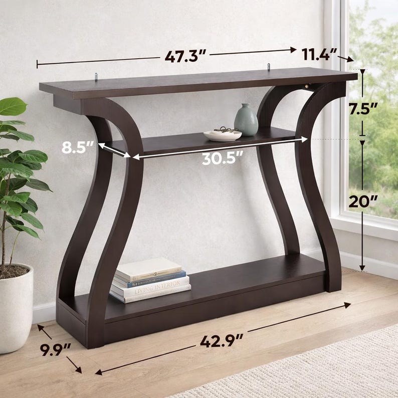 May include: A dark brown console table with curved side supports, a top surface, a middle shelf, and a bottom base. Dimensions are labeled as 47.3 inches wide, 11.4 inches deep, 7.5 inches shelf height, 20 inches shelf clearance, and 42.9 inches base.