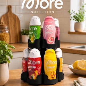 Könnte beinhalten: Ein schwarzer drehbarer Ständer mit mehreren Flaschen More Nutrition Zerup aromatisiertem Sirup. Die Flaschen haben verschiedene Farben und Etiketten wie Pink Peach, Peach Iced Tea und Pineapple, jeweils mit weißem Verschluss und ohne Zucker.