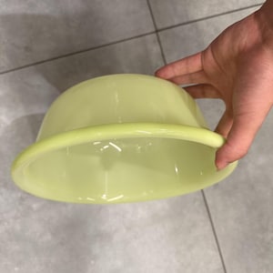 May include: A pale yellow, smooth, semi-translucent bowl with a wide, rounded rim. The bowl features a glossy finish and a deep, curved basin, showcasing a simple, functional design with a consistent light yellow colour throughout the entire object.