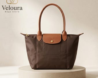 Bolsa de lona marrom em nylon com detalhes em couro, dobrável, para transporte no ombro e muito mais.