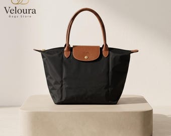 Bolsa grande preta de nylon com detalhes em couro, dobrável, ideal para viagens.