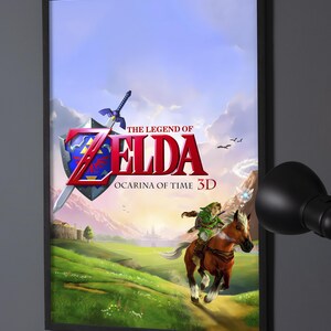 Peut inclure: Une affiche verticale encadrée présentant l'illustration de The Legend of Zelda Ocarina of Time 3D. L'image montre un personnage en vêtements verts chevauchant un cheval brun dans un champ, avec un emblème d'épée et de bouclier au-dessus du titre.