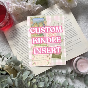 May include: A rectangular Kindle insert featuring a light pink and white checkered background with collage-style illustrations of frogs, flowers, and envelopes. The text CUSTOM KINDLE INSERT is printed in large, bold, white letters across the centre.