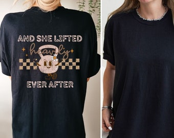 May include: Black t-shirt with a graphic of a pink kettlebell with a flower and the text "And she lifted heavily ever after".