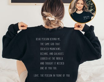 May include: Black sweatshirt with a white text message that reads "Dear person behind me. The same God that created mountains, oceans, and galaxies looked at the world and thought it needed one of you too. Love, the person in front of you."