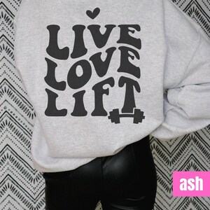 May include: A grey sweatshirt with the text "LIVE LOVE LIFT" in a retro font with a small heart above the word "LIVE" and a dumbbell icon below the word "LIFT".