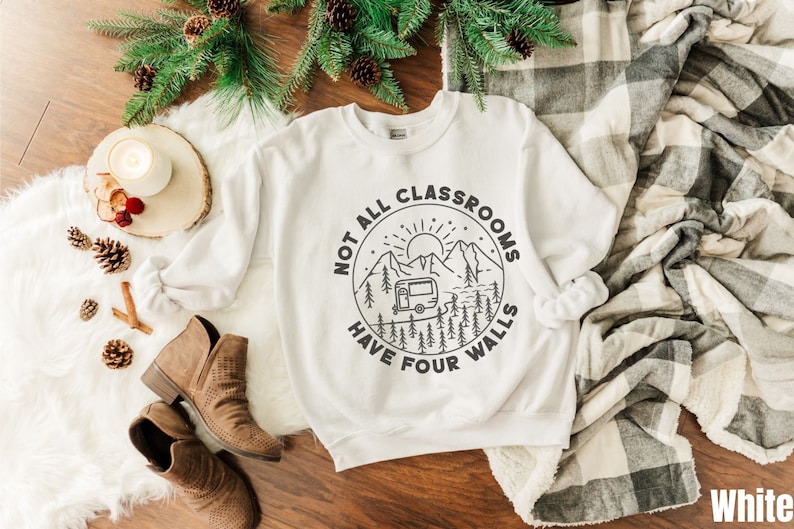 K&ouml;nnte beinhalten: Wei&szlig;er Pullover mit einem schwarz-wei&szlig;en Grafikdesign eines Wohnmobils in einer Berglandschaft. Der Text lautet "Not all classrooms have four walls".