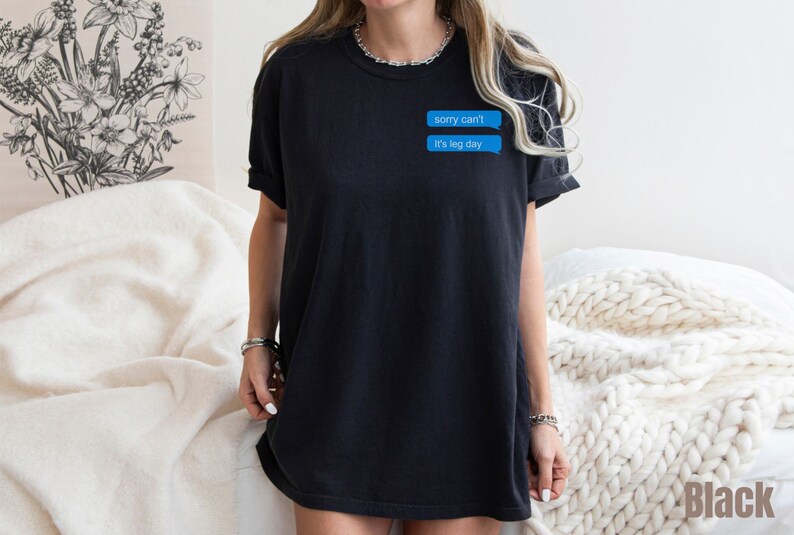 Może przedstawiać: Czarny, oversize'owy t-shirt z niebieskim nadrukiem wiadomości tekstowej, na kt&oacute;rym widnieje napis "sorry can't it's leg day"