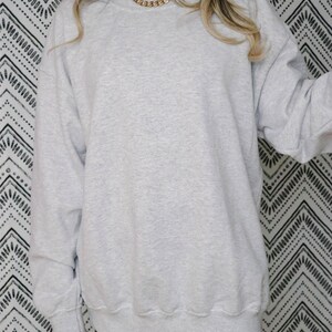 May include: An oversized grey sweatshirt with a crew neck. The sweatshirt is made from a soft, comfortable material.
