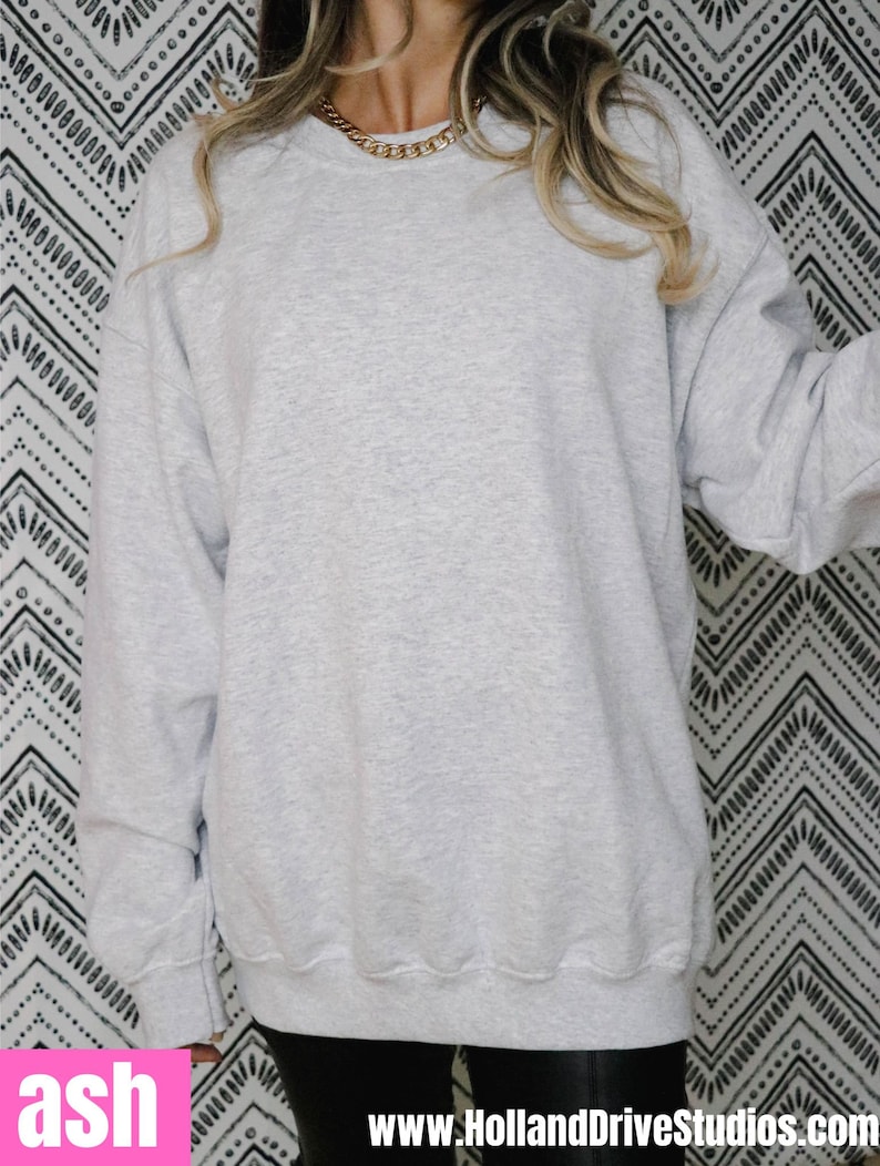 May include: An oversized grey sweatshirt with a crew neck. The sweatshirt is made from a soft, comfortable material.