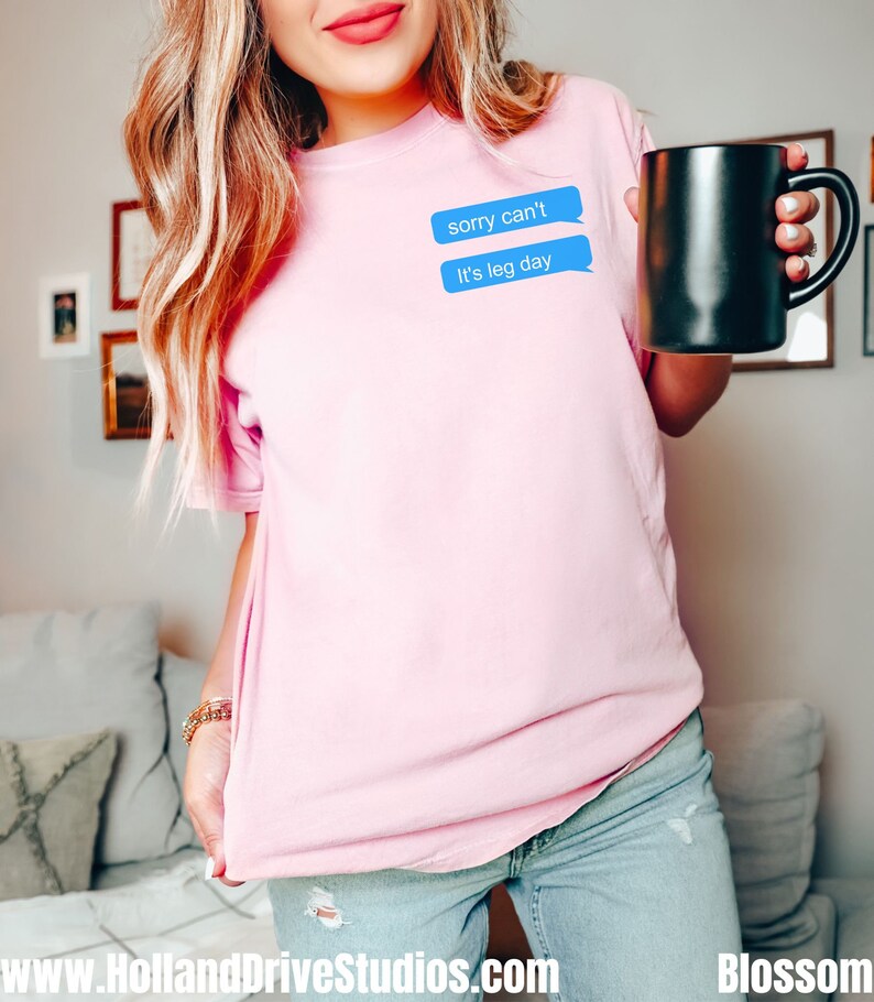 Może przedstawiać: R&oacute;żowy t-shirt z niebieskim graficznym elementem w kształcie dymku z tekstem "sorry can't it's leg day".