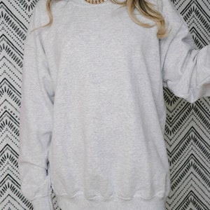 Puede incluir: Una sudadera gris de gran tama&ntilde;o con cuello redondo. La sudadera est&aacute; hecha de un material suave y c&oacute;modo.