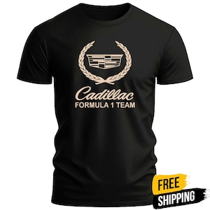 May include: A black short-sleeved t-shirt featuring a beige graphic on the chest. The graphic displays the Cadillac logo enclosed in a laurel wreath, with the text Cadillac FORMULA 1 TEAM printed in beige lettering directly underneath the emblem.
