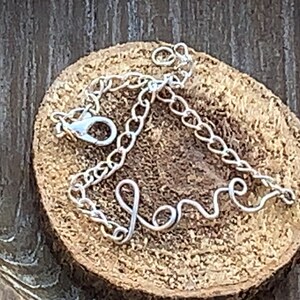 May include: A silver chain bracelet with the word "love" spelled out in cursive.