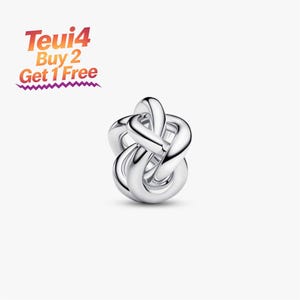 Może przedstawiać: Polerowany srebrny charms o skomplikowanym, splecionym wzorze węzła z gładkimi, zaokrąglonymi powierzchniami. Tekst Teui4 Buy 2 Get 1 Free znajduje się w lewym górnym rogu, napisany gradientową czcionką od pomarańczowego do fioletowego z ząbkowanym podkreśleniem.