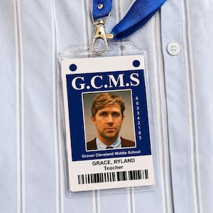 Puede incluir: Un porta credencial de plástico transparente con un cordón azul sujeto a una camisa de rayas azul claro. La credencial muestra el texto G.C.M.S, Grover Cleveland Middle School, el nombre GRACE, RYLAND, el título Teacher, un retrato y un código de barras.