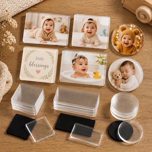 Può includere: Una collezione di calamite fotografiche in acrilico trasparente di forma rettangolare e circolare. Alcune presentano fotografie di neonati, mentre una calamita rettangolare mostra il testo little blessings con un cuore. Include pezzi in acrilico vuoti e supporti magnetici neri.