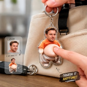 May include: A custom acrylic keychain featuring a person's face on a small figure wearing an orange t-shirt and gray sweatpants with a soft, squishy belly. The keychain includes a metal ring and is displayed with text reading 1. UPLOAD, 2. WE MAKE IT! and SQUISH IT ANYTIME!