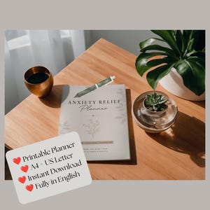 Könnte beinhalten: Ein weißes Anxiety Relief Planner Heft mit einer floralen Strichzeichnung, einem grünen Stift, einem Kupferbecher und einer kleinen Sukkulente in einer Glasschale. Eine weiße Karte mit roten Herzsymbolen zeigt den Text: Printable Planner, A4 + US Letter, Instant Download, Fully in English.