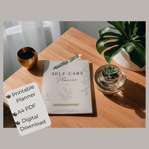 Könnte beinhalten: Ein Self-Care-Planer mit dem Titel "SELF-CARE Planner" und dem Text "A SELF-CARE PLANNER FOR A CALM & BALANCED LIFE" liegt auf einem Holztisch. Ein Stift, eine kleine Sukkulente in einem Glasbehälter, eine goldene Tasse und eine Pflanze in einem weißen Topf befinden sich ebenfalls auf dem Tisch. Eine Karte lautet "Printable Planner, A4 PDF, Digital Download."