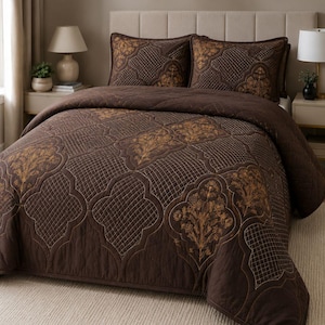 Peut inclure: Une courtepointe marron foncé et deux taies d'oreiller assorties présentant un motif répétitif de grands médaillons floraux dorés brodés et une texture finement quadrillée. L'ensemble de literie est conçu avec une finition matelassée.