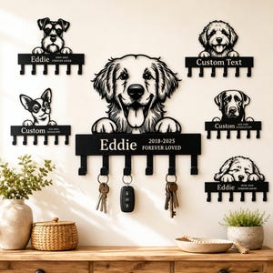 Pode incluir: Porta-chaves de metal preto com silhuetas de cães e ganchos. Os porta-chaves têm os nomes "Eddie" e "Custom Text" com o texto "2018-2025 Forever Loved". Chaves e uma chave do carro estão penduradas nos ganchos.