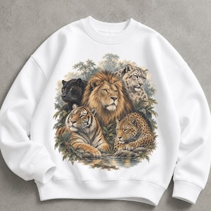 May include: A white crewneck sweatshirt featuring a detailed graphic print of a lion, a tiger, a black panther, a leopard, and a snow leopard surrounded by foliage. The animals are positioned together in a naturalistic scene with a water reflection.
