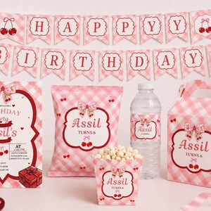 Peut inclure: Un ensemble de fête d'anniversaire avec un motif vichy rose et blanc et des cerises. Il comprend une bannière Happy Birthday, une invitation personnalisée pour Assil, un sachet de snacks, une étiquette de bouteille, un pot à pop-corn et une boîte cadeau.