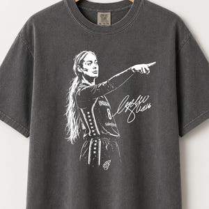 May include: A charcoal grey short-sleeve t-shirt featuring a white graphic print of a basketball player pointing. The player wears a jersey with the number 8 and the text Indiana. A white signature is printed next to the player on the front.