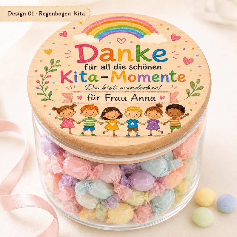 May include: A clear glass jar filled with pastel-colored wrapped candies, topped with a round wooden lid. The lid features a colorful rainbow, floral accents, and the German text: Danke f&uuml;r all die sch&ouml;nen Kita-Momente, Du bist wunderbar! f&uuml;r Frau Anna.