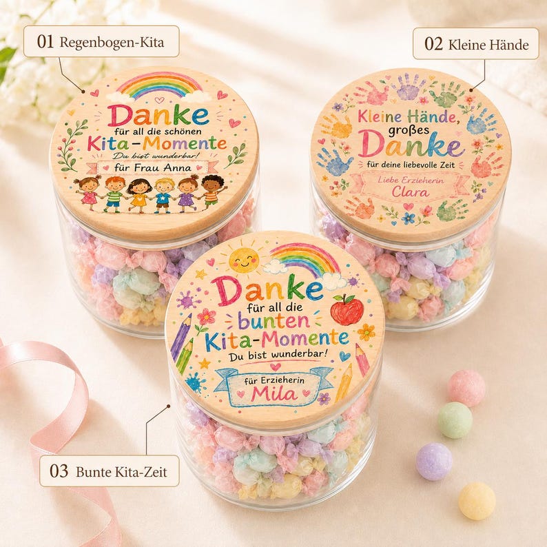 May include: Three clear glass jars filled with pastel-colored wrapped candies, each topped with a round wooden lid featuring colorful illustrations and German text. The lids display designs including rainbows, handprints, pencils, and children.