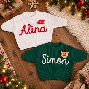May include: A white knit sweater with the red embroidered name Alina and a small red hat patch, and a dark green knit sweater with the white embroidered name Simon and a small reindeer patch, both featuring long sleeves and crew necklines.
