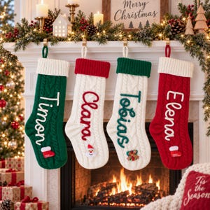 May include: Four cable-knit Christmas stockings hanging in a row. The first is green with a white cuff and the name Timon. The second is white with a red cuff and the name Clara. The third is white with a green cuff and the name Tobias. The fourth is red with a white cuff and the name Elena.