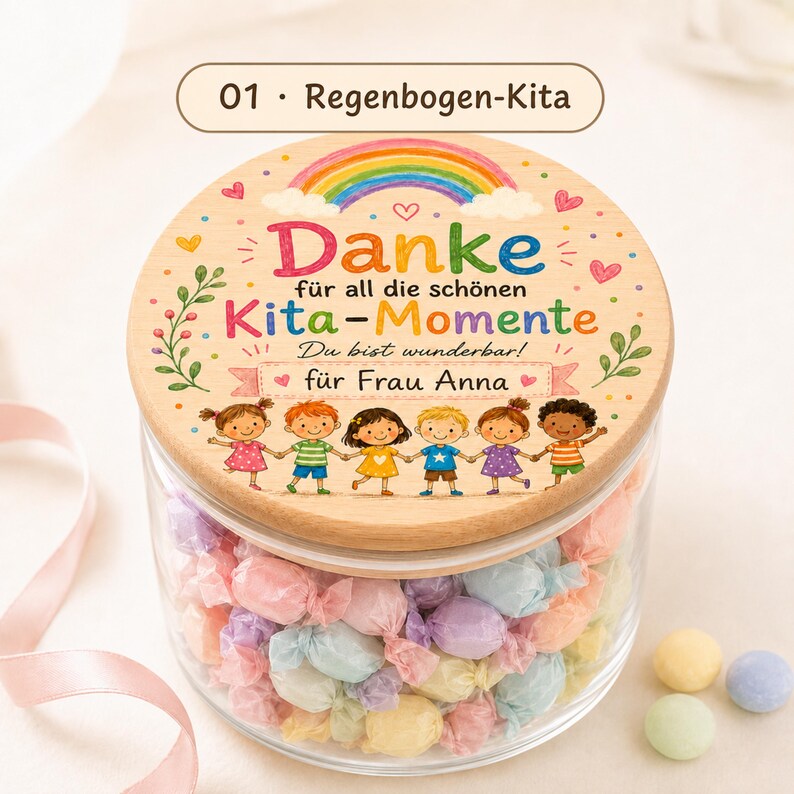 Puede incluir: Un frasco de vidrio transparente lleno de dulces envueltos en colores pastel, con una tapa redonda de madera. La tapa presenta un arco&iacute;ris colorido, seis ni&ntilde;os ilustrados tomados de la mano y el texto en alem&aacute;n Danke f&uuml;r all die sch&ouml;nen Kita-Momente, Du bist wunderbar, f&uuml;r Frau Anna.