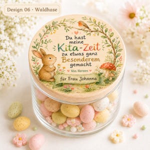 May include: A clear glass jar with a round wooden lid featuring a printed illustration of a brown rabbit, a bird, a mushroom, and floral greenery. The text reads: Du hast meine Kita-Zeit zu etwas ganz Besonderem gemacht Von Herzen f&uuml;r Frau Johanna.