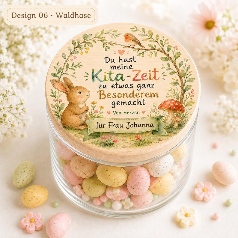 May include: A clear glass jar with a round wooden lid featuring a printed illustration of a brown rabbit, a bird, a mushroom, and floral greenery. The text reads: Du hast meine Kita-Zeit zu etwas ganz Besonderem gemacht Von Herzen f&uuml;r Frau Johanna.
