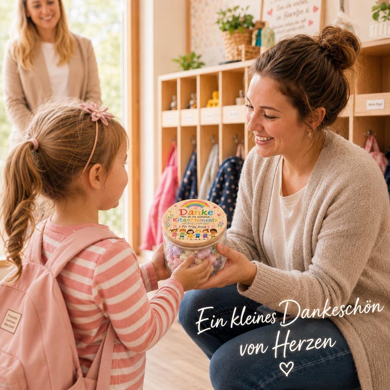 May include: A clear glass jar with a wooden lid featuring a colorful rainbow graphic, the text "Danke Kita-Momente", and illustrations of children. The jar is filled with small, multi-colored paper hearts, serving as a thoughtful gift.