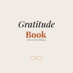 Può includere: Una copertina di diario color crema con le parole "Gratitude Book" in lettere nere e arancioni. Sotto il titolo c'è "(The LDR Edition)" in caratteri neri più piccoli. Un simbolo di infinito in basso.