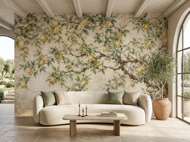 May include: A wall mural featuring a sprawling lemon tree with yellow fruit and green leaves against a textured beige background. A curved cream-colored sofa with green and beige throw pillows sits in front of the mural, with a wooden coffee table.