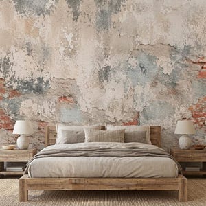 Puede incluir: Un dormitorio con una estructura de cama de madera, ropa de cama beige, dos mesitas de noche de madera con lámparas blancas y un mural de pared que muestra un muro de ladrillo desgastado con yeso descascarado en tonos grises y rojos.