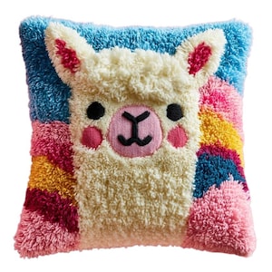 May include: A square throw pillow featuring a textured punch needle design of a cream-colored llama face. The background displays a vibrant rainbow pattern with stripes of blue, pink, yellow, and dark red. The llama has black eyes and a pink nose.